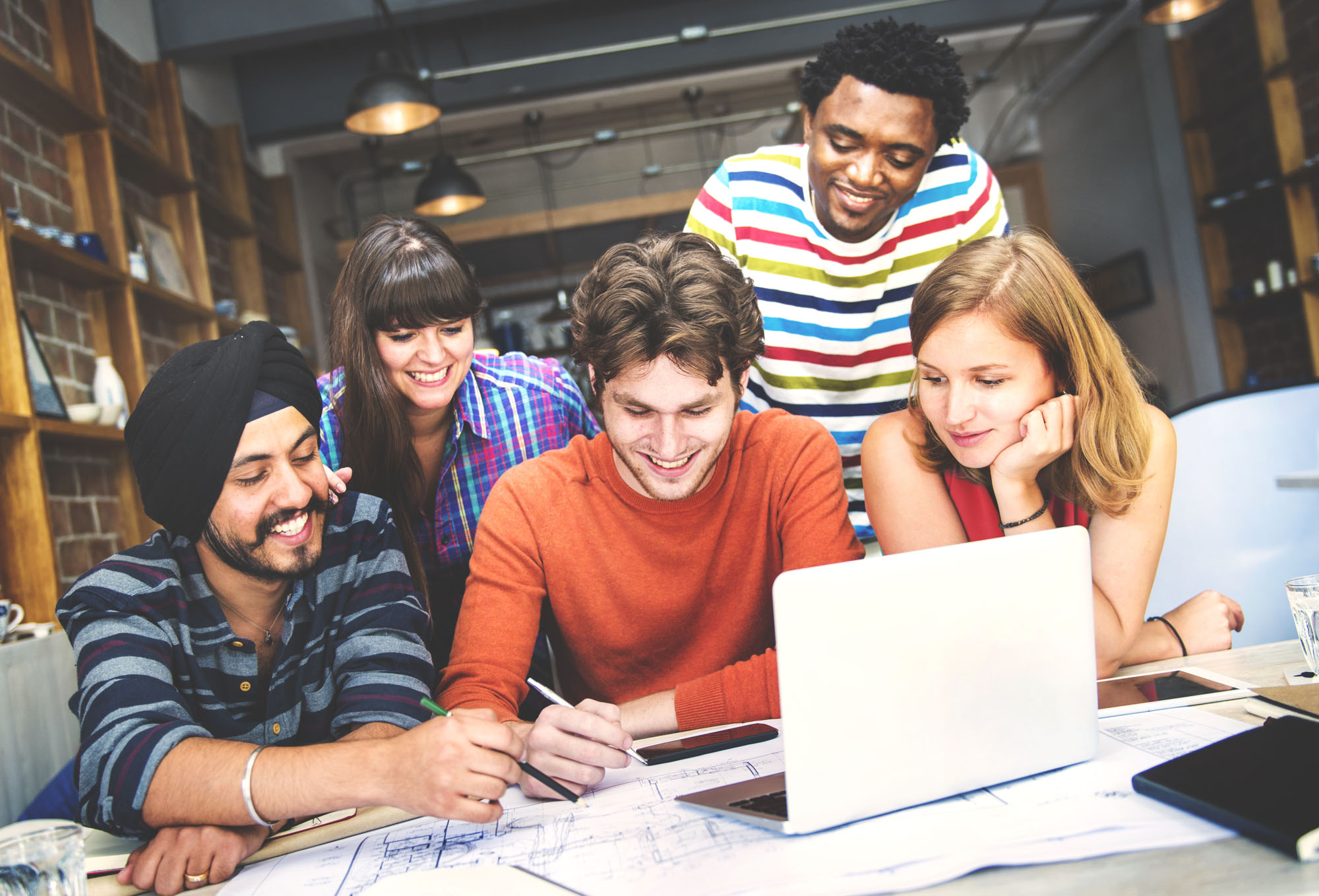 Group of people working together in front of a laptop